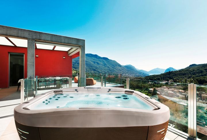 an outdoor hot tub on a raise deck with glass railings